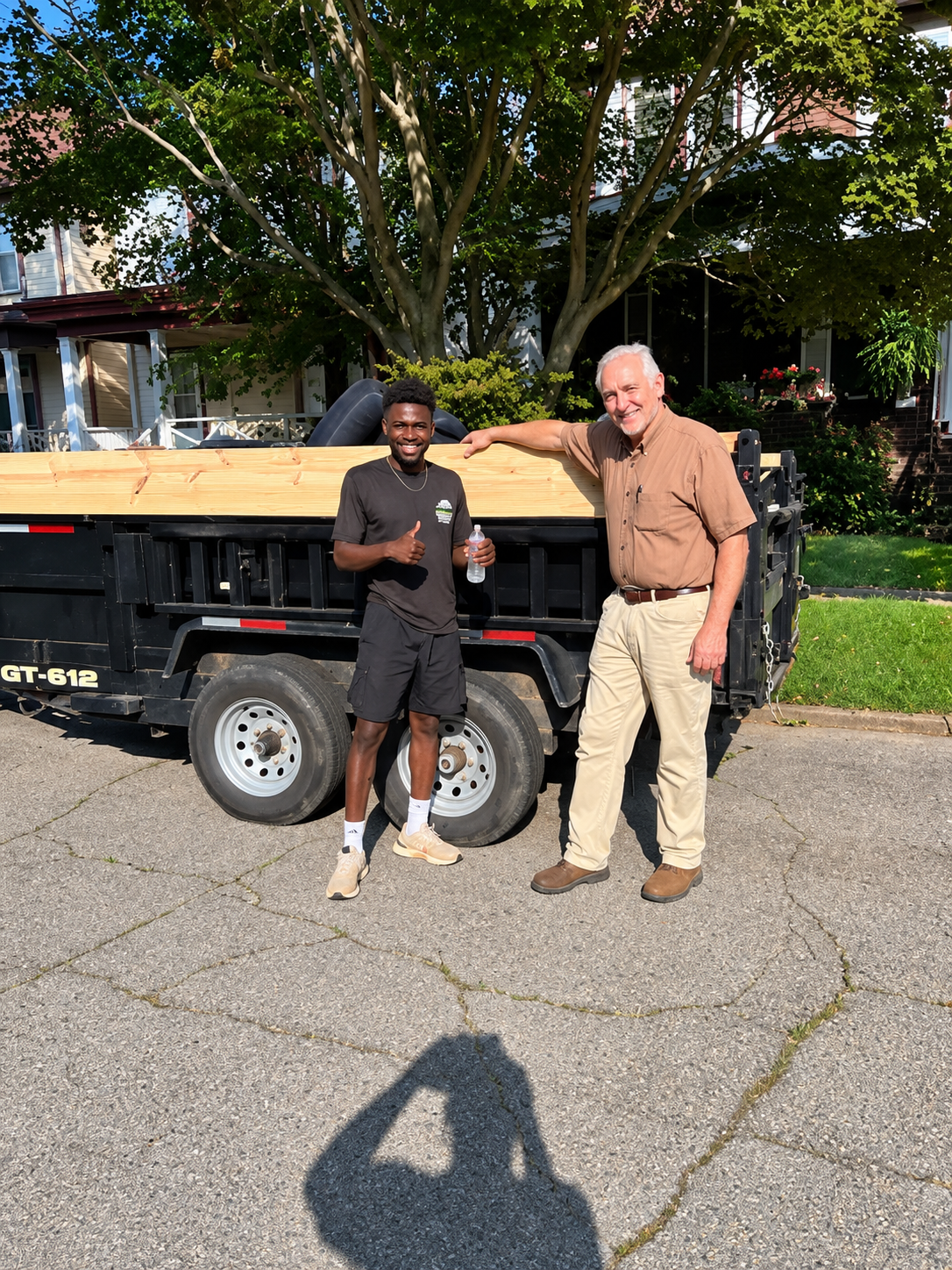 Paul's Junk Removal and Demo team beside a lumber-laden trailer